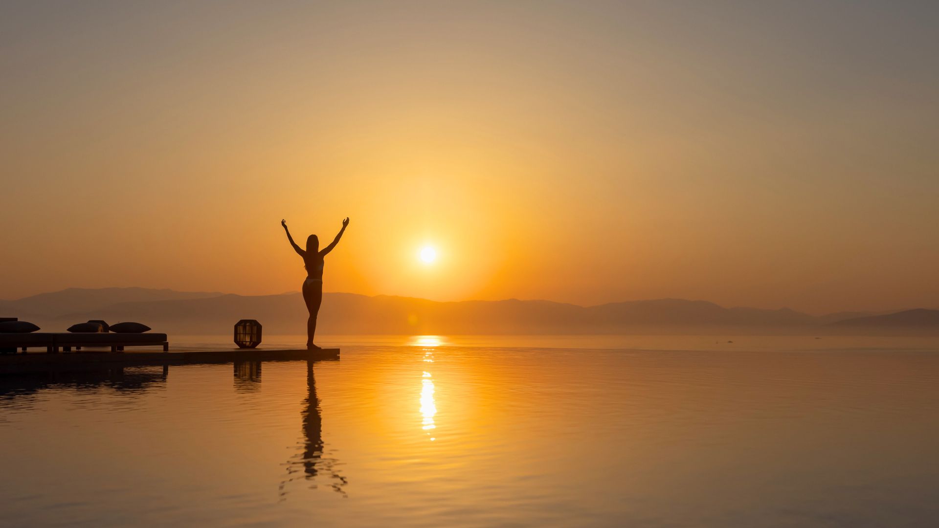 woman by the infinity pool at sunrise in corfu